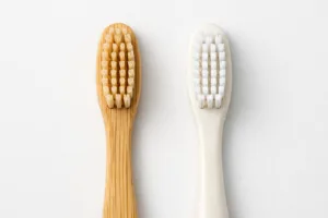 This image presents both a bamboo and a bioplastic toothbrush next to each other, highlighting their material differences and eco-friendly design.