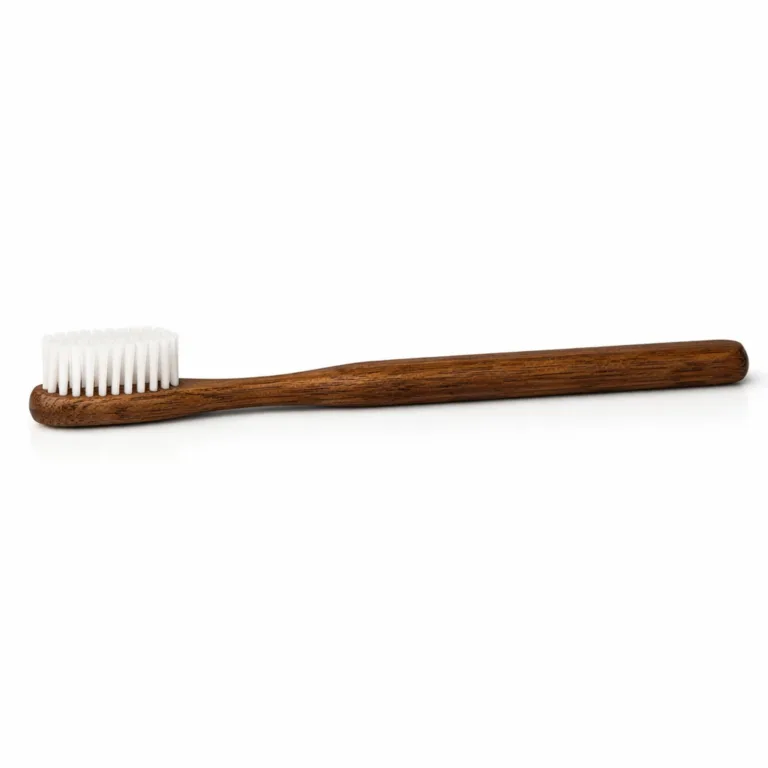 This adult bamboo toothbrush features a carbonized bamboo handle with a straight, classic profile. The handle displays a rich brown tone from carbonization, paired with ultra-soft white nylon bristles. A refined alternative for natural oral hygiene.