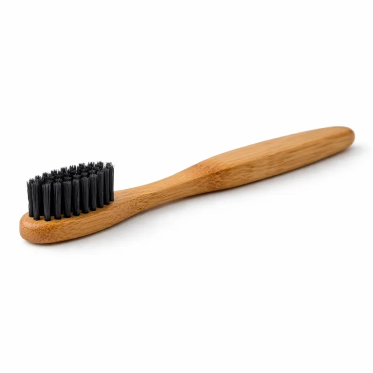 Studio photo of a Bamboo Charcoal Bristle Toothbrush featuring a dark carbonized bamboo handle with beveled edges and black charcoal bristles. Designed for enhanced durability and comfort.