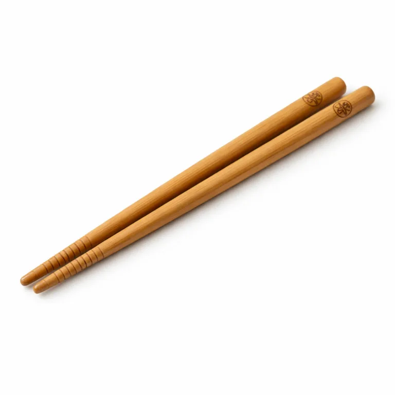 A manufactured pair of bamboo chopsticks with a matte-oiled finish, round profile, and precise anti-slip grooves at the tip. The logo is subtly engraved near the tip, providing both style and secure grip.