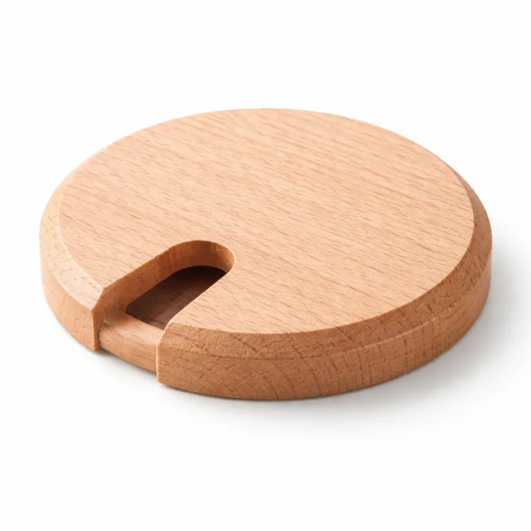 A round wooden cable management grommet made from beech wood that features a beveled edge for a modern touch and a cable slot for cord organization.