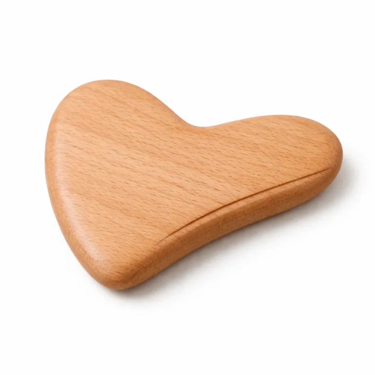 Product photo of an ergonomically heart-shaped gua sha massager crafted from beech wood, finished with a matte oil for a soft touch and accented with a shallow groove designed to enhance massage technique. Displayed on a white studio background for clarity.