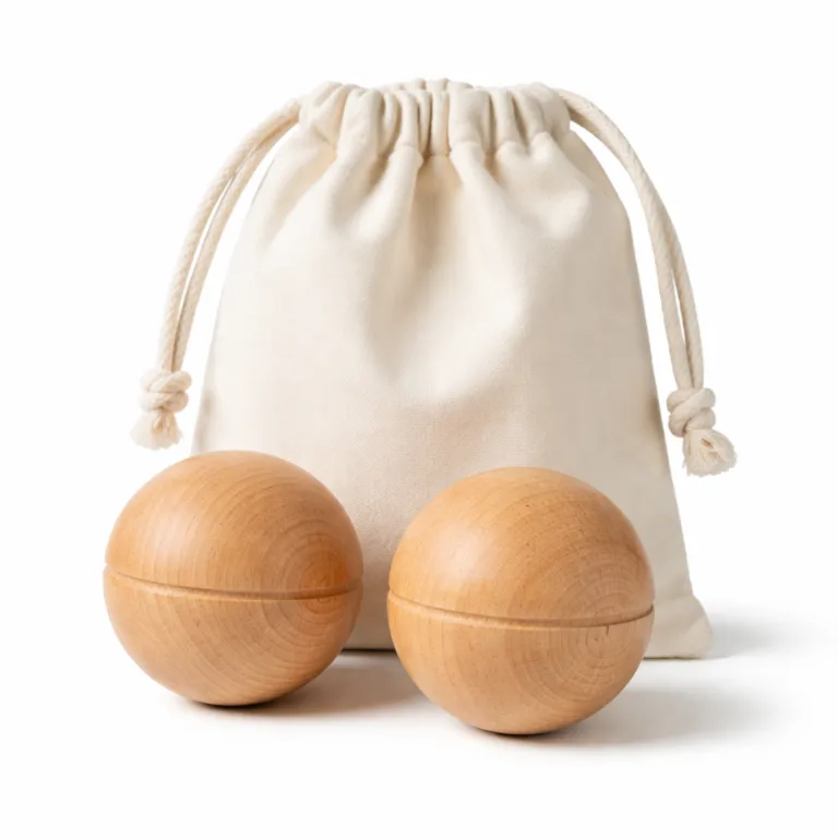 A pair of beech wood massage balls, each designed with a single, shallow groove for enhanced grip and tactile interest. Set includes a soft cotton pouch for storage.