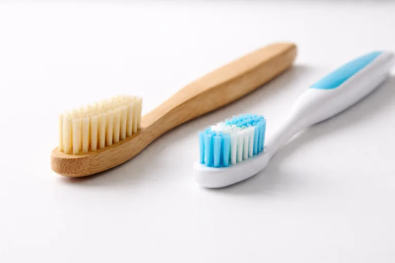 A photorealistic image comparing a bamboo and a plastic toothbrush side by side, highlighting their material differences and environmental context.
