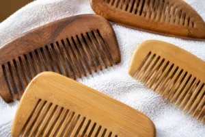 A collection of wooden and bamboo combs arranged on a towel, highlighting their craftsmanship and suitability for detangling wet hair.